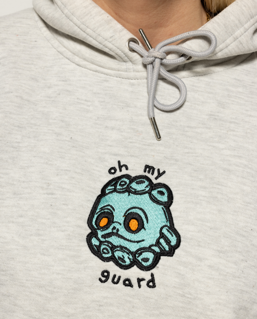 Closeup of gray hoodie with turquoise creature on the chest