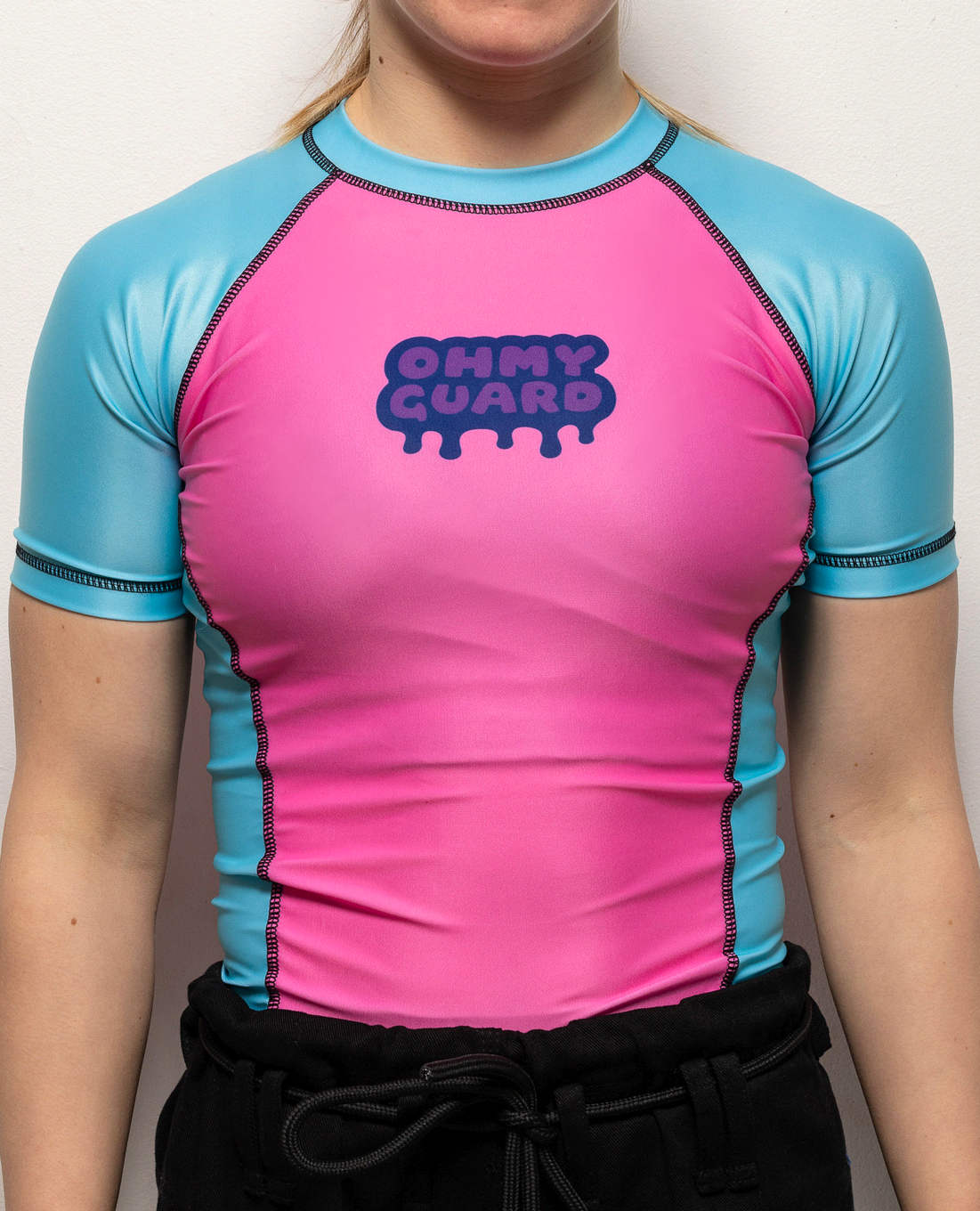 Front view of a woman in a pink and blue shortsleeve rashguard