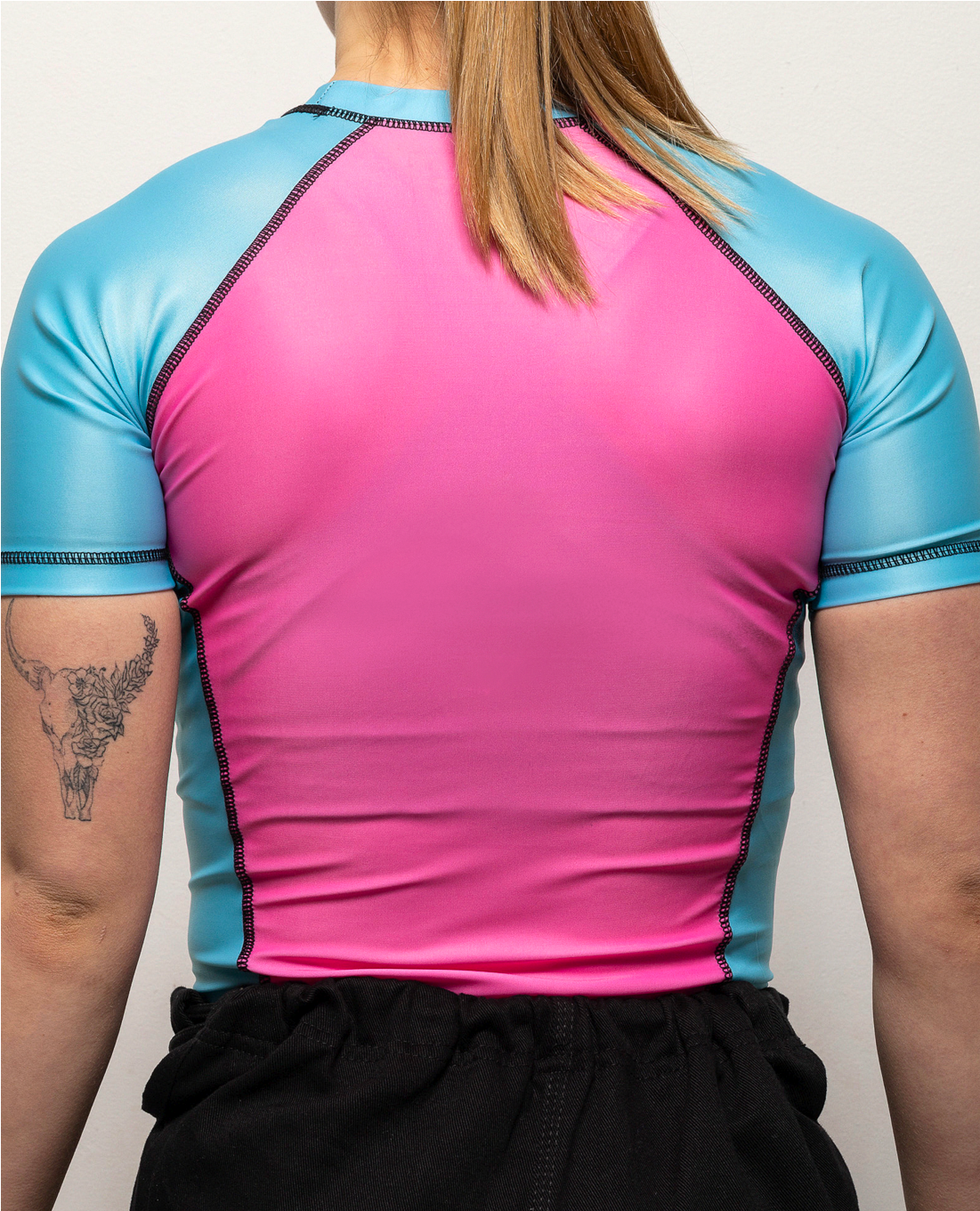 Back view of a woman in a pink and blue shortsleeve rashguard