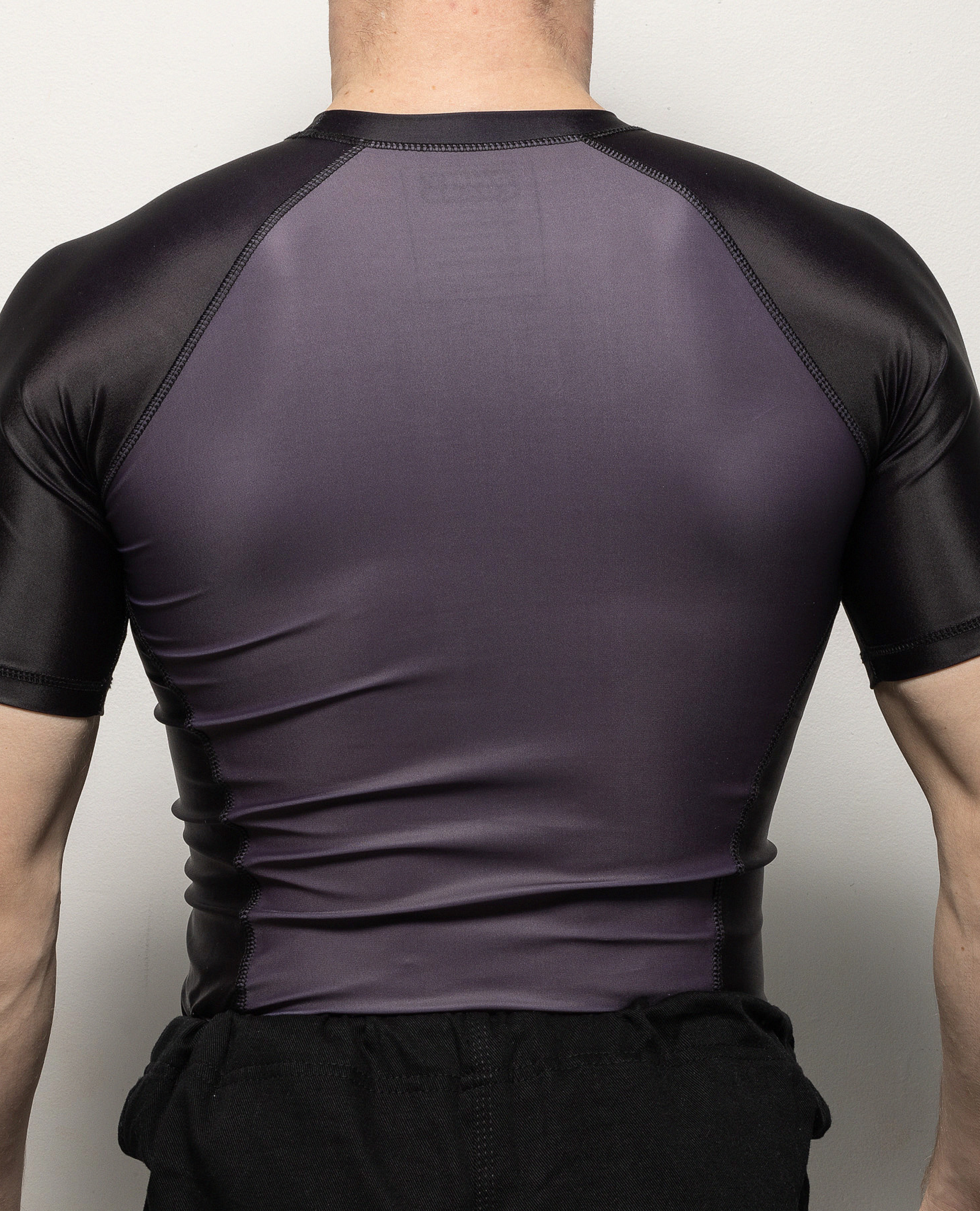 Back view of a man in a black and grey shortsleeve rashguard